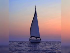 A stunning sailboat glides across the water at sunset, showcasing the beauty of sailing adventures on the open sea.