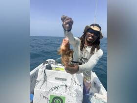 A fisherman proudly displays his catch while out on the water, showcasing the excitement of a successful fishing trip.
