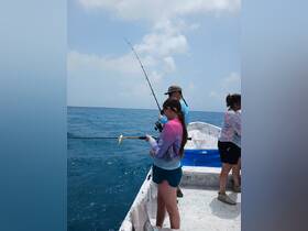 A group of friends enjoys a fishing trip on the open ocean, showcasing the excitement of reeling in a catch. Perfect for adventure seekers and fishing enthusiasts.