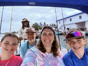 A joyful family poses for a selfie aboard a fishing boat, ready for an exciting day on the water. The vibrant atmosphere captures the essence of family bonding and adventure.
