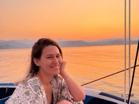 A woman smiles while enjoying a serene sunset on a boat, capturing the essence of relaxation and beauty on the water.