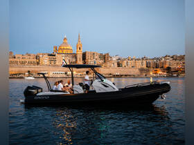 A lively group enjoys an evening on a sleek boat, with the stunning cityscape of Valletta illuminated in the background — perfect for memorable outings on the water.