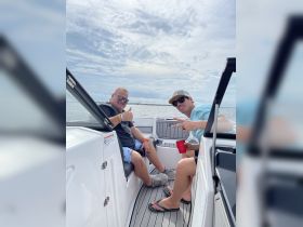 Two friends enjoy a fun day on the water, relaxing on a boat with drinks in hand — perfect for summer outings and celebrations.