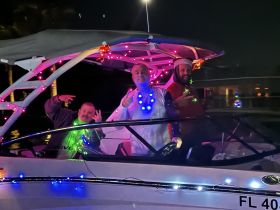 A festive group celebrates on a decorated boat at night, showcasing vibrant lights and a joyful atmosphere — perfect for holiday gatherings on the water.