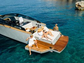 A lively group enjoys a sunny day on a luxury yacht, sipping drinks and sunbathing on the deck — the perfect setting for a summer getaway.