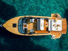 Aerial view of a group enjoying a luxurious day on a boat, sunbathing and relaxing on plush seating, surrounded by crystal-clear waters — perfect for summer outings.