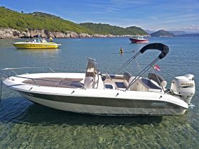 A scenic view of a boat anchored in clear waters, with people swimming nearby, showcasing a perfect day at the beach.