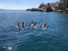 A group of friends enjoys a refreshing swim in crystal-clear waters, creating unforgettable memories in a stunning coastal setting.