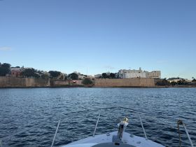 A picturesque view from the bow of a boat, showcasing the historic coastline and buildings along the harbor — perfect for exploring scenic waterfronts.