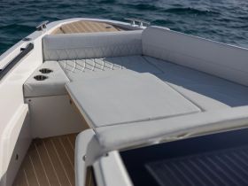 A stylish lounge area inside a boat, featuring comfortable seating and cup holders, perfect for relaxing while enjoying the water.