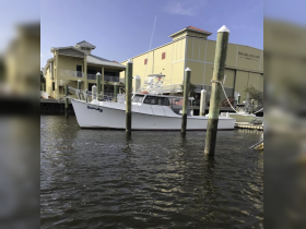 A fishing boat named 'Beppe' docked at a marina, showcasing its sleek design against a backdrop of waterfront buildings.