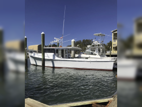 A well-maintained boat docked at the marina, showcasing its sleek design against a clear blue sky.
