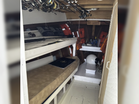 Interior view of a boat cabin featuring seating and fishing gear, ideal for relaxing and preparing for fishing adventures.
