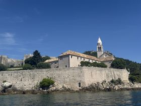 A picturesque view of a historic building along the coastline, showcasing stunning architecture against a clear blue sky — a perfect backdrop for exploring the area's rich history.
