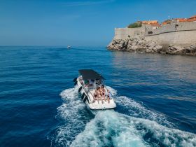 A lively group enjoys a scenic boat cruise along the coastline, showcasing the beautiful waters and historic architecture in the background.