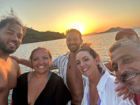 A joyful group of friends captures a sunset selfie on a boat, celebrating their time together on the water — perfect for memorable outings and gatherings.