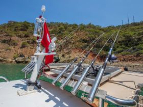 A close-up view of fishing rods and equipment on a boat, showcasing the perfect setup for a day of fishing in serene waters.