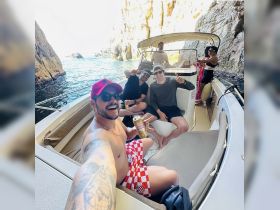 A group of friends enjoys a fun day on the boat, capturing the moment with smiles and drinks in a picturesque coastal setting.