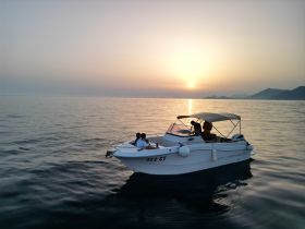 A couple enjoys a romantic sunset cruise on a boat, creating a picturesque moment on the water with stunning views.