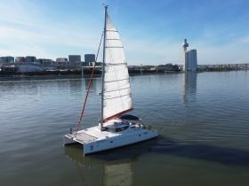 A stunning aerial view of a catamaran sailing smoothly on calm waters, with a modern city skyline in the background, perfect for showcasing sailing adventures.