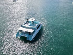 Aerial view of a boat underway, showcasing its vibrant design against sparkling waters — perfect for exploring coastal destinations.