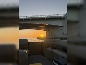A serene sunset view from the deck of a Bentley pontoon boat, showcasing the tranquil waters and a nearby dock — perfect for evening cruises.