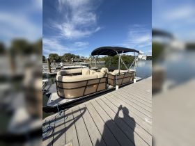 A pontoon boat docked at the marina, featuring comfortable seating and a sunny day backdrop — perfect for family outings or leisurely cruises.