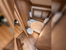 A clean and well-designed bathroom inside a boat, featuring a toilet and sink, ideal for comfort during trips at sea.