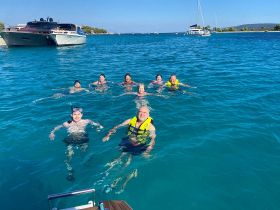 A lively group enjoys snorkeling and swimming in crystal-clear waters, creating unforgettable memories on their aquatic adventure.