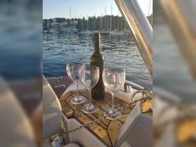 A bottle of wine and three glasses elegantly arranged on a boat's deck, perfect for a relaxing evening on the water.