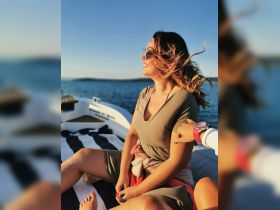 A joyful moment captured on a boat as a woman enjoys the sunshine and the beautiful water views, perfect for a relaxing day on the sea.