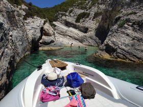 Guests enjoy a refreshing swim in a secluded cove with crystal-clear waters, perfect for a relaxing day on the boat.