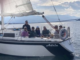 A cheerful group enjoys a sailing adventure aboard the 'Adria,' capturing the essence of friendship and fun on the water.