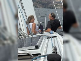 A couple enjoys a relaxing moment aboard a sailboat, sharing laughter and drinks while taking in the scenic views — perfect for a romantic sailing experience.