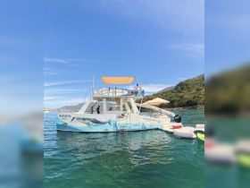 A vibrant catamaran named 'Margarita' is anchored in clear waters, with guests enjoying the sun and scenery — perfect for local tours and aquatic adventures.