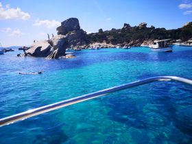 A vibrant scene of snorkeling in crystal-clear waters near a rocky island, showcasing the beauty of a perfect day on the water.