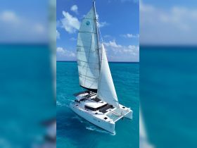 An aerial view of a sleek catamaran sailing through vibrant turquoise waters, showcasing its elegant design and perfect for luxury charters.
