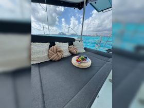 A cozy seating area on a boat featuring decorative pillows and a platter of fresh fruit, perfect for enjoying snacks while cruising on the water.