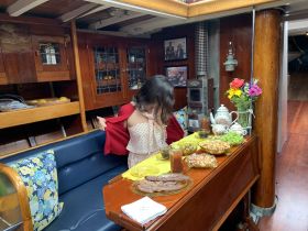 A child enjoys a cozy dining experience inside a boat cabin, surrounded by a delightful spread of snacks and drinks, perfect for family outings on the water.