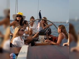A lively group of friends enjoys a sailing trip, sharing drinks and laughter aboard the boat, perfect for memorable celebrations on the water.