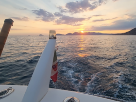 A serene sunset view from the bow of a boat, showcasing the tranquil waters and distant islands — perfect for romantic evening cruises.