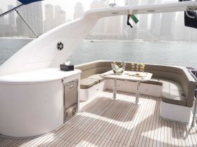 A stylish interior view of a yacht's lounge area featuring comfortable seating and a table set for drinks, perfect for relaxing while enjoying the waterfront scenery.