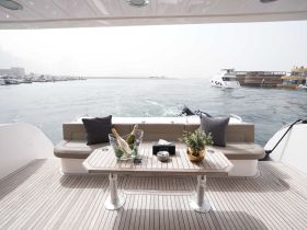 A stylish interior view of a yacht's lounge area featuring comfortable seating and refreshments, perfect for relaxing while enjoying the scenic waterfront.