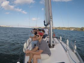 A group of friends enjoys a sailing adventure, sipping drinks and taking in the stunning views of the coastline and bridge — perfect for memorable outings on the water.
