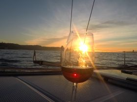 A glass of wine captures the stunning sunset view from a yacht, perfect for romantic evenings or sunset cruises on the water.