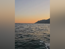 A serene sunset view over the ocean, showcasing the beautiful coastline — perfect for capturing the tranquility of a boating experience.