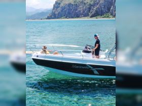 A couple enjoys a sunny day on a boat, surrounded by clear turquoise waters and stunning scenery — perfect for a relaxing getaway.