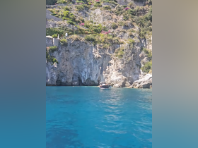 A picturesque view of a boat navigating through crystal-clear waters, surrounded by stunning cliffs and lush greenery, perfect for exploring coastal landscapes.