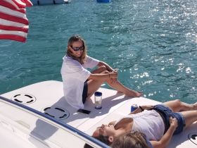 Two friends enjoy a sunny day on the boat, relaxing and sunbathing on the deck — a perfect setting for summer fun and social gatherings on the water.