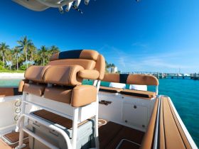 A well-designed helm seating area on a boat, showcasing comfortable seating and a scenic backdrop of palm trees and clear waters, perfect for a day out on the water.